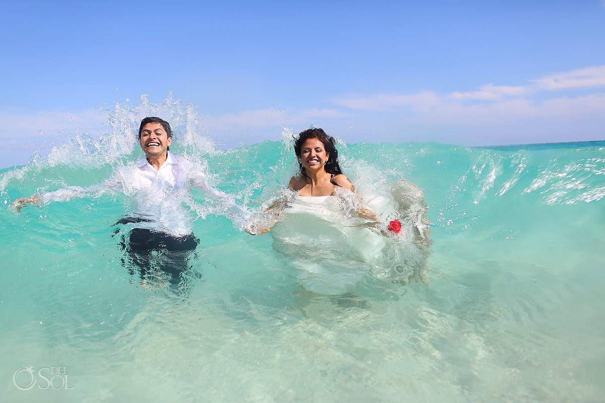 Bride and groom in a wave in the Caribbean Sea trash the dress photo shoot