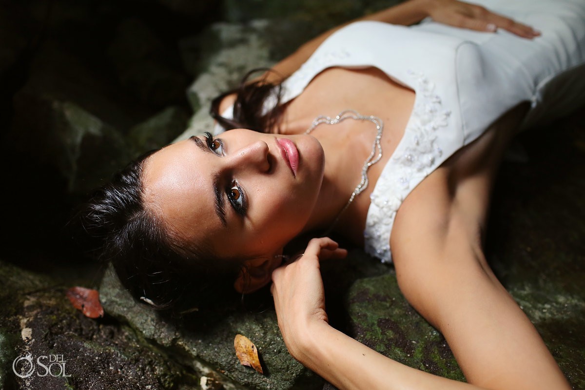 Beautiful bride laying down on the rocks in a cenote Riviera Maya