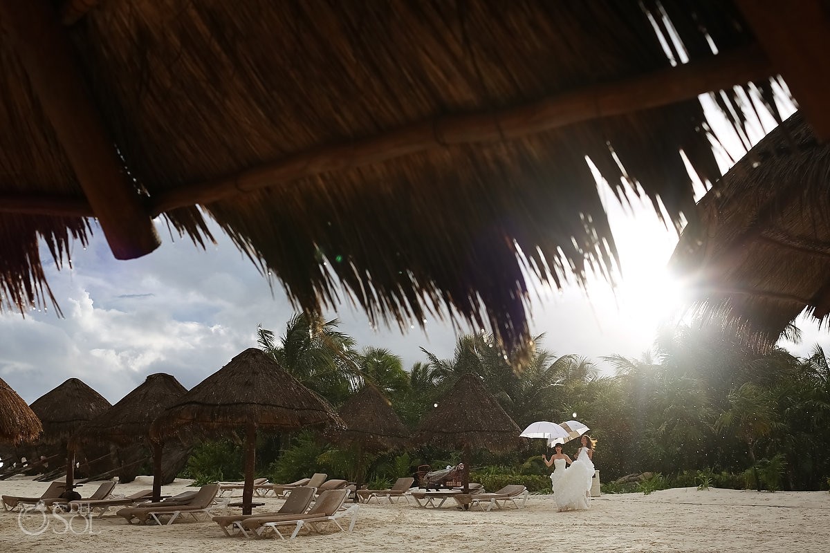 bride walks on the rainy beach for destination wedding at secrets maroma hotel