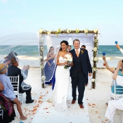 Guests shake maracas as bride and groom exit beach wedding at belmond maroma resort