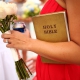 Bridesmaid holding a corona cerveza beer, bouquet, and a holy bible in a red dress