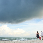 Parents child walking Caribbean beach rain clouds storm waves Playa Paraiso Riviera Maya Mexico