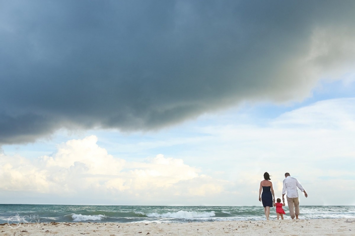 Parents child walking Caribbean beach rain clouds storm waves Playa Paraiso Riviera Maya Mexico