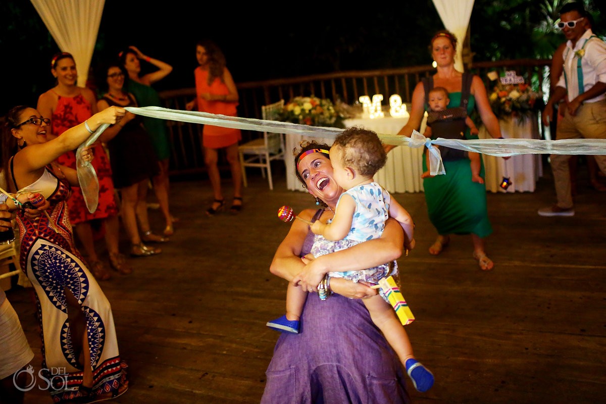 palapa destination wedding reception games guest and baby doing the limbo Grand Sirenis Riviera Maya Mexico