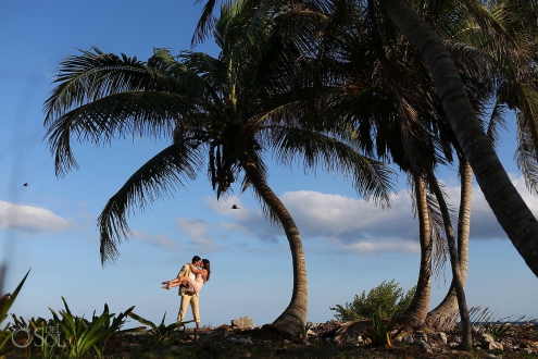 couple under palm trees with birds flying past Grand Sirenis Riviera Maya Save the Date Engagement Session