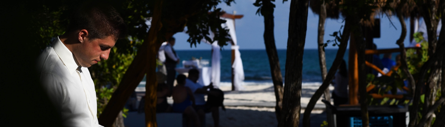 groom in a patch of sunlight reading his vows before his Iberostar Paraiso del Mar beach wedding