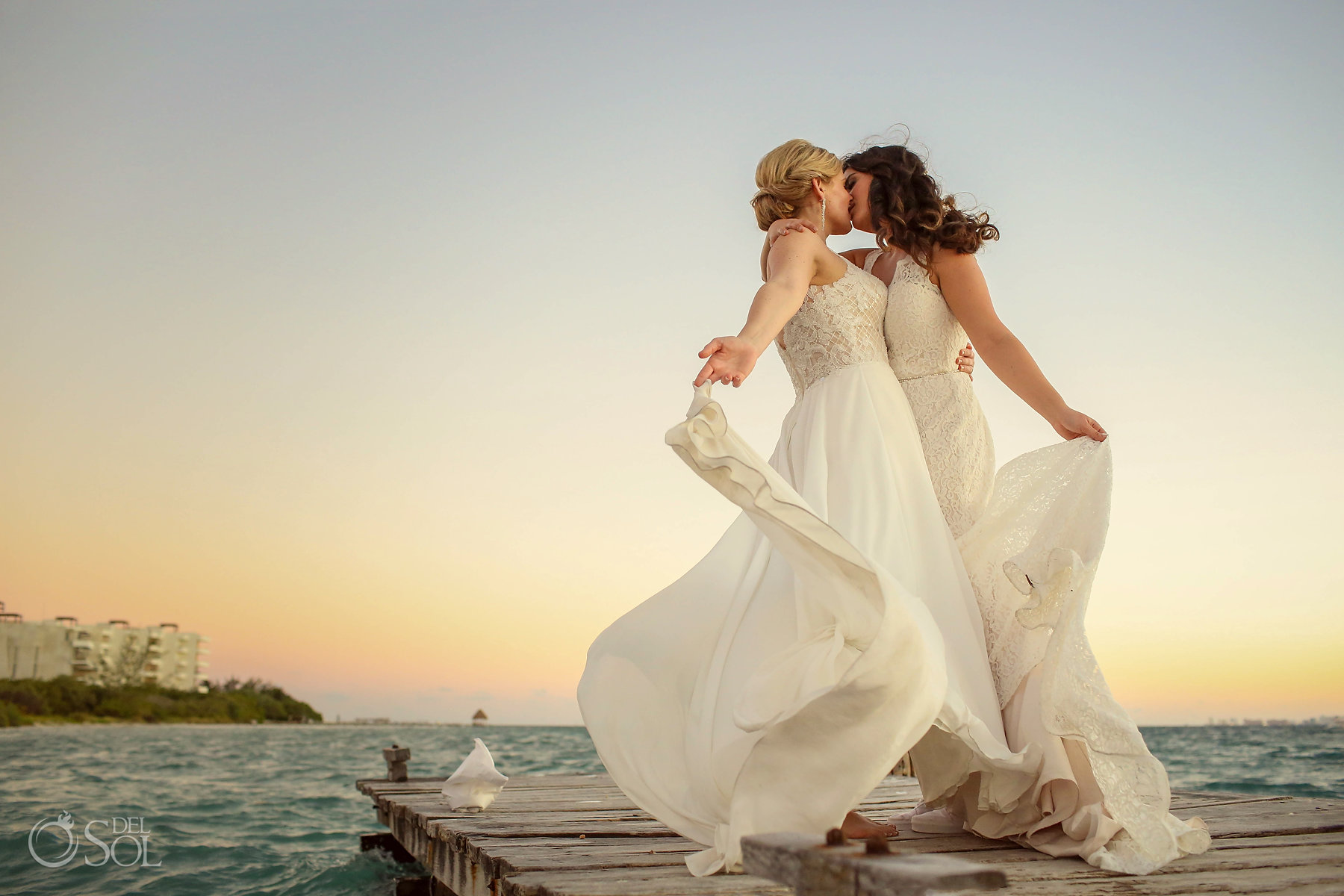 Lesbian brides kissing over a pier Isla Mujeres queer wedding Zama Beach