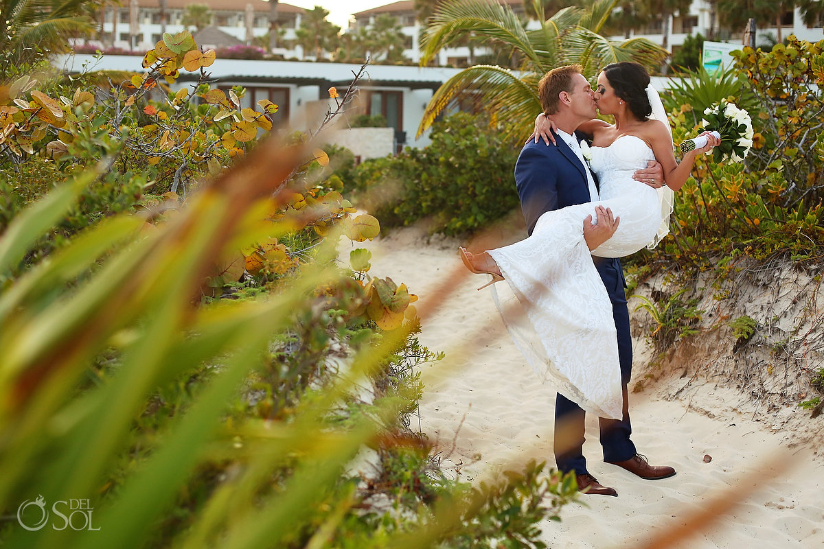 groom carring bride kissing her on the way to the beach Secrets Playa Mujeres