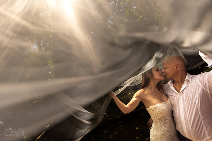 bride and groom posing under a veil