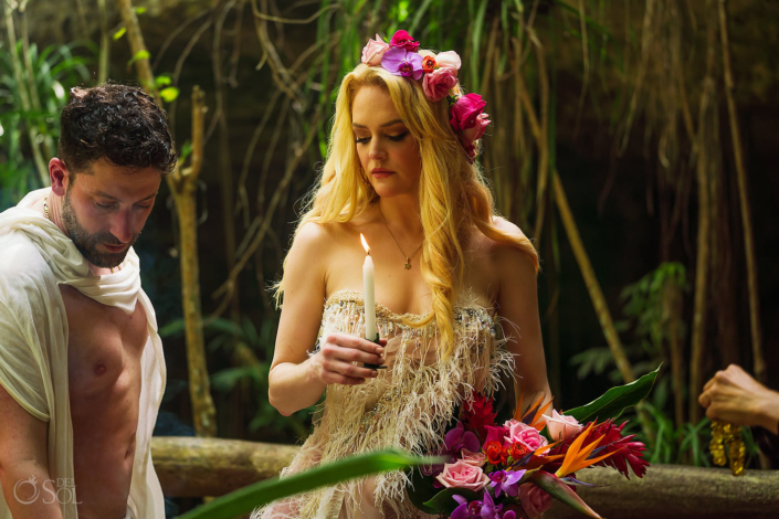 Bride wearing feather wedding dress and pink orchid flower crown holds a candle