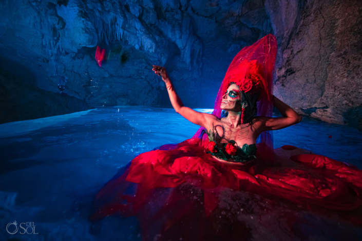 photoshoot inspired by the day of the dead model in the water wearing red dress and headdress and skull makeup