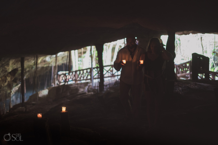 couple enter a cave holding candles as part of their cenote tour