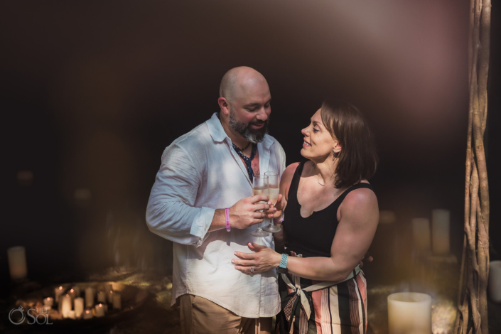 couple share champagne toast to celebrate getting engaged in a private cenote Tulum Mexico