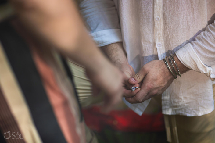 groom holds beautiful cushion cut engagement ring between his fingers