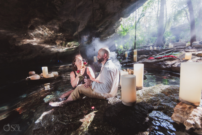 newly engaged fiancee splashes her fiance with water from a red rose in a Tulum Private cenote