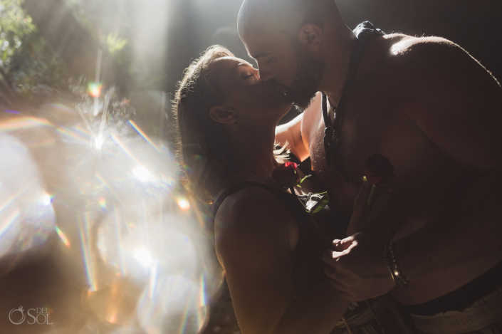 romantic proposal photographer captures couple kissing in the Tulum jungle holding a red rose