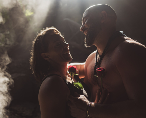 bare chested groom to be shows off his muscles in romantic engagement photo holding his newly engaged fiancee and 2 red roses