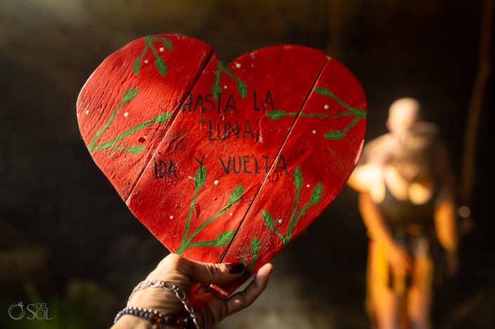 photographer holding hand painted wooden heart sign that says to the moon and back in Spanish