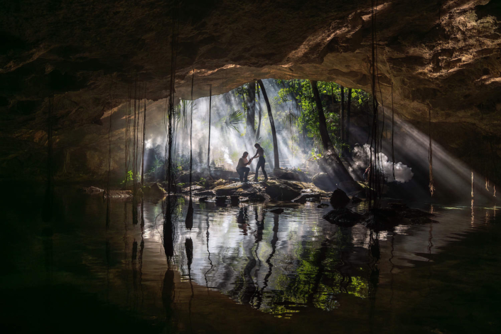 Luxury cenote engagement photography in the Riviera Maya with dramatic rock formations and tropical atmosphere