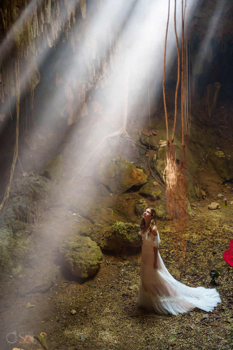 Underground cenote environment illuminated by epic light beam from the sun with a beautiful bride