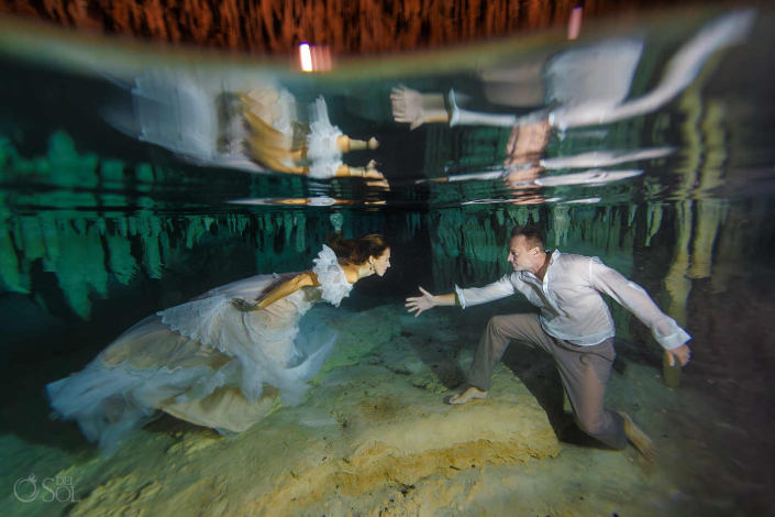 Couple exploring a hidden cenote cave together underwater
