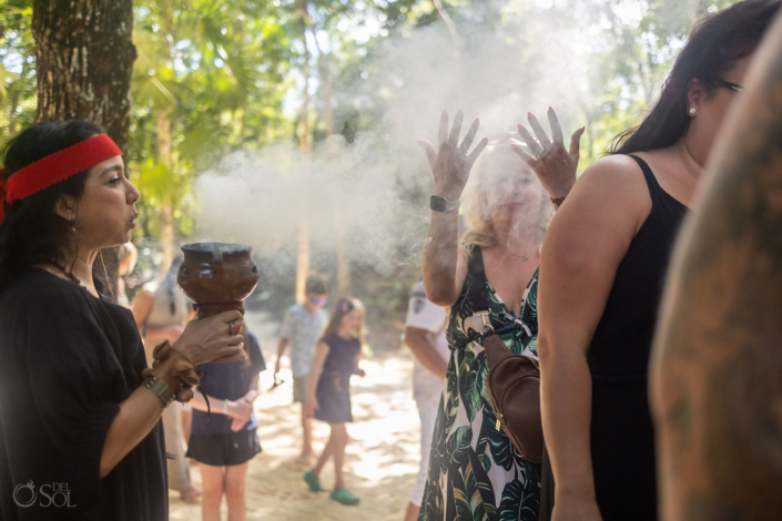Wedding officiant blessing copal resin during a spiritual cenote wedding ceremony in Mexico.