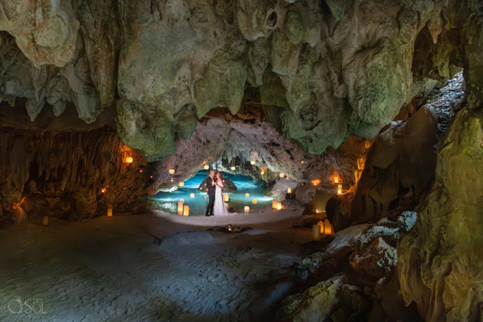 lots of candles reflecting across the turquoise water inside the cenote.
