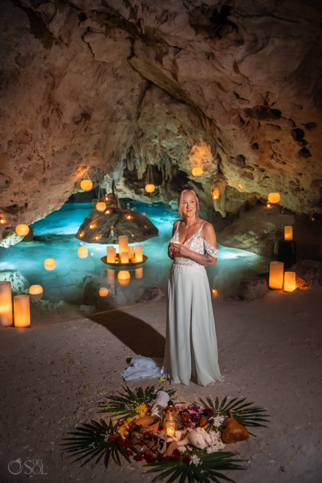 Bride standing beside candlelight inside a natural cave during her cenote wedding.