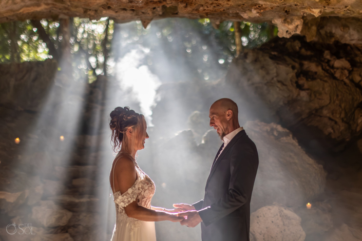 Natural sunbeams illuminate the couple during their cenote wedding ceremony.