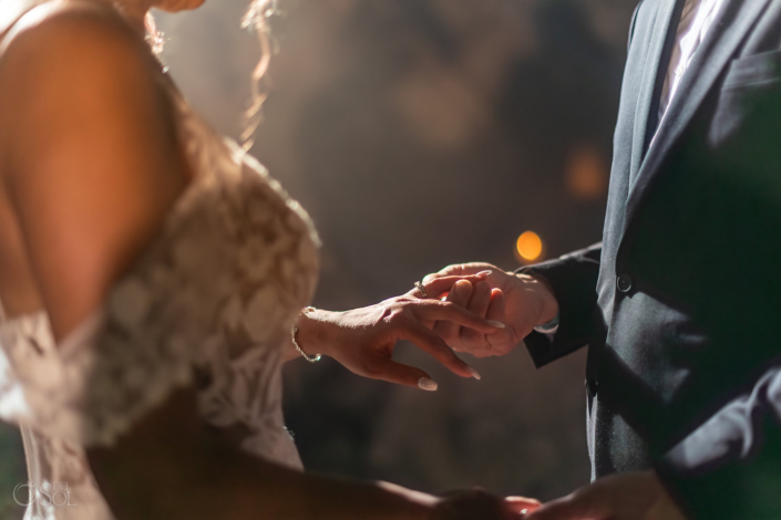 Close-up of the wedding ring exchange during a cenote ceremony.
