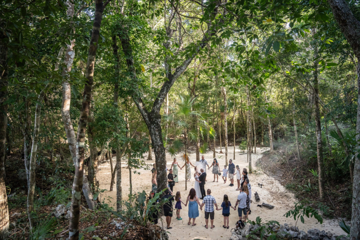 Family gathered outside the cenote holding hands for a unity blessing cenote ceremony in the jungle