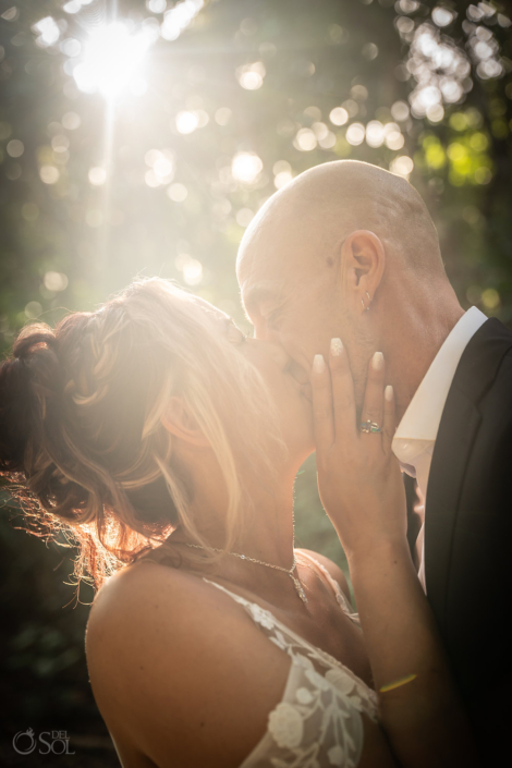Bride and groom sharing a kiss surrounded by warm jungle light.