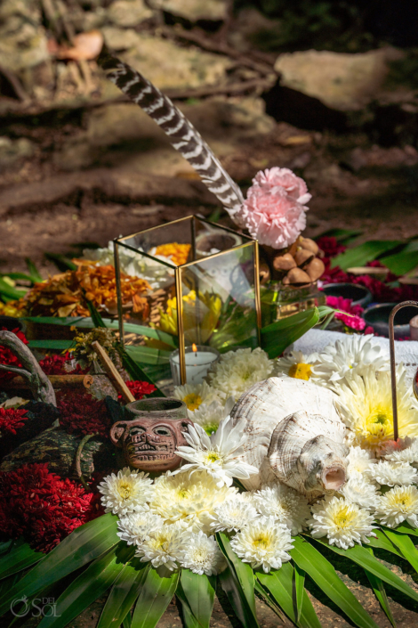 Mayan-inspired ceremony details with flowers and candles.