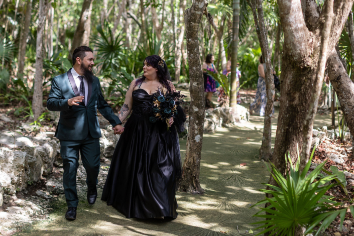 Bride in a black wedding dress beneath jungle light.