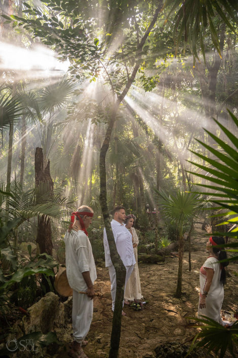 Couple standing beneath enormous beams of sunlight inside a Mexican cenote