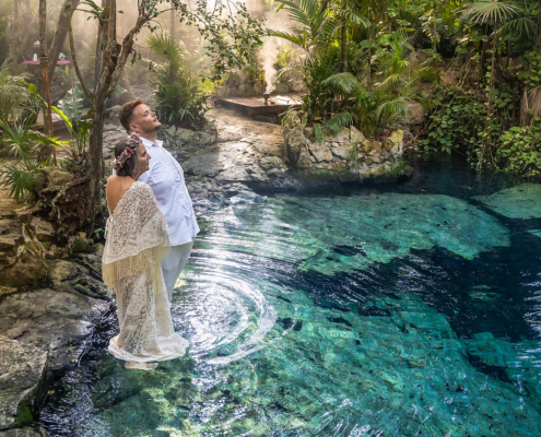 Couple stands in the water inside a private cenote wedding ceremony in the Riviera maya Mexican jungle