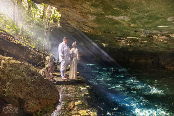 Intimate wedding ceremony surrounded by jungle, smoke and morning sunlight in a Riviera Maya cenote