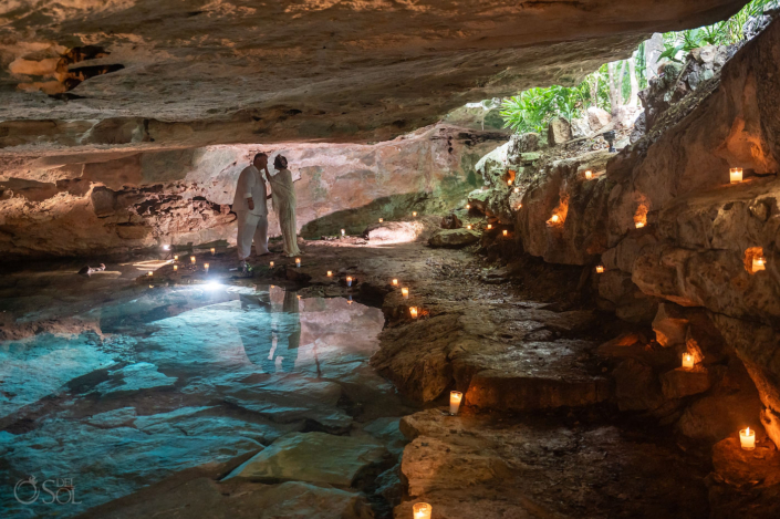 Dramatic cenote wedding portrait with reflected light, water and limestone cave walls