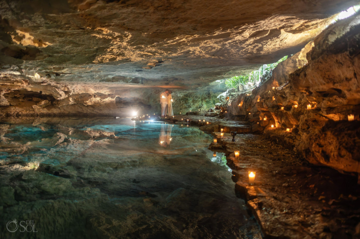 Couple standing together inside a candlelit cenote after their spiritual wedding ceremony